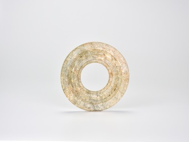 A Jade Ring with Concentric Grooves, Shang Dynasty (circa 1600&ndash;1046 BC) Carved from a mottled grey-green jade with areas of russet