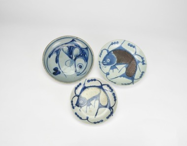 A Group of Three Blue and White and Underglaze Copper-Red &lsquo;Fish&rsquo; Dishes, Late Ming to Early Qing Dynasty, 17th Century