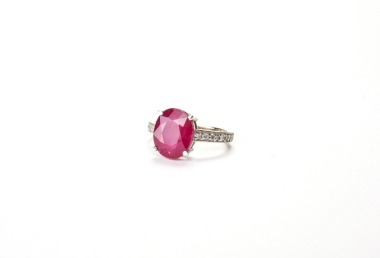 A 14K White Gold Ruby and Diamond Ring, Set with an oval-cut ruby, red in color with natural inclusions, mounted in 14K white gold.