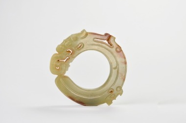 A Celadon And Russet Jade Dragon-Form Ring Pendant. Shang Dynasty
